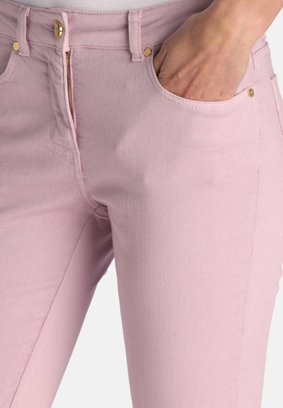 Jean en denim rose à coupe ajustée, doté d'une braguette zippée, de poches avant et d'accents de ferrures dorées. Texture lisse avec des coutures visibles.