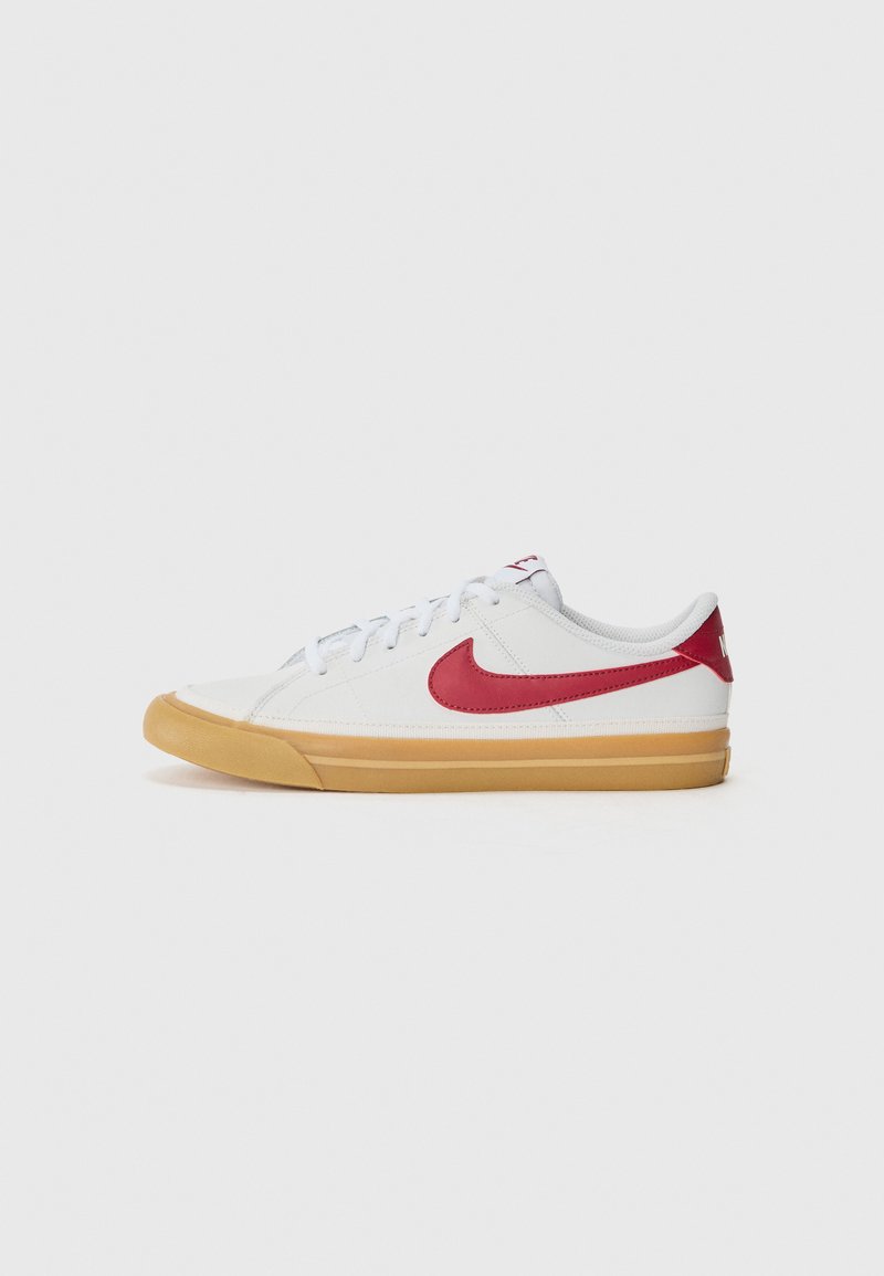 Hvit sneaker med rødt Swoosh-logo, teksturert kanvasoverdel, flate lisser og gummisåle; lav profil, minimale sømmer.