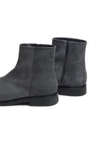 Bottines en suède gris avec une texture lisse, fermeture éclair sur le côté et un design minimaliste. Semelle en caoutchouc avec un motif de semelle discret.