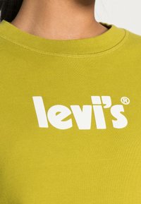 Sudadera de algodón verde con cuello redondo y ribetes acanalados, que presenta un gran logo blanco de "levi's" en el pecho.