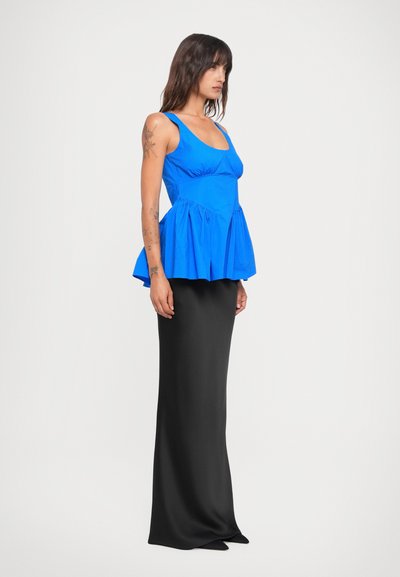 Peplum top in bright blue cotton blends with a sleek black floor-length skirt, featuring smooth texture and fitted silhouette.