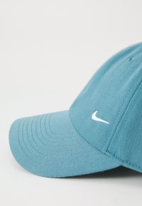 Casquette de baseball bleu clair en coton avec une visière pré-incurvée. Équipée d'un logo Nike blanc brodé sur le panneau avant.