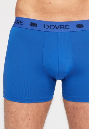 Blå herreboxershorts med en blød elastisk talje, præget med "IDOVRE" og et bisonlogo. Glat stof med en tætsiddende pasform.
