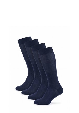 Four pairs of dark blue knee-high socks standing upright in a row against a white background.