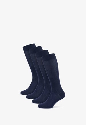 Vier Paare dunkelblaue knielange Socken stehen aufrecht in einer Reihe vor weißem Hintergrund.