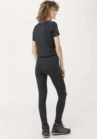 Haut noir à manches courtes et leggings ajustés en tissu extensible, avec des coutures flatlock et une texture lisse. Porté avec des bottes de randonnée robustes.