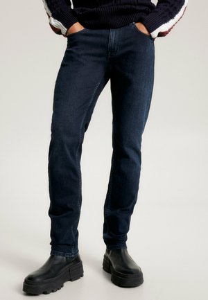 Jeans in denim blu scuro con vestibilità slim, dotati di cinque tasche e dettagli di cucitura sottili. Abbinati a stivali piattaforma neri e chunky.