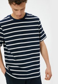Marineblå og hvid stribet t-shirt med korte ærmer, rund hals, afslappet pasform og blød tekstur. Vandrette striber jævnt fordelt.