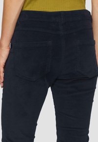 Marineblauwe corduroy broek met een slim fit, heeft een hoge taille, twee achterzakken en een zachte ribbelstructuur.