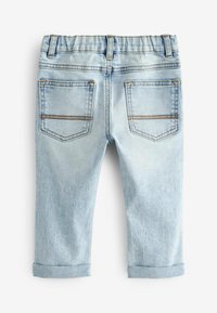 Pantalon en denim bleu clair avec une taille élastique, des ourlets repliés et deux poches arrière avec une double couture. Texture lisse.