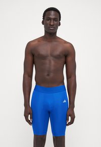 Kék sportos rövidnadrág szStretchy anyagból, széles derékrésszel és fehér logóval a bal lábszáron. Elegáns dizájn, testre szabott sziluett.