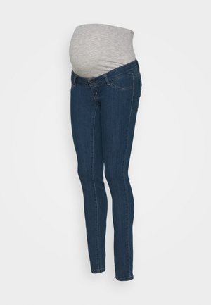Jean de maternité extensible bleu foncé avec une ceinture élastique grise conçue pour s'adapter au ventre d'une femme enceinte.