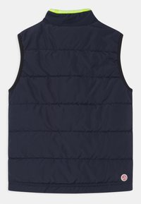 Marineblaue, gepolsterte ärmellose Weste mit schwarzem Besatz, Stehkragen mit limettengrünem Text und kleinem runden Logo nahe dem unteren Saum.