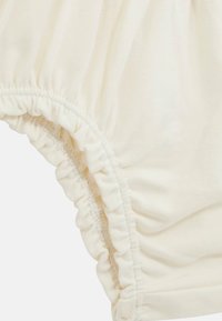 Tessuto color crema con texture arricciata in vita e alle aperture delle gambe, che evidenzia un materiale morbido e elasticizzato progettato per il comfort.