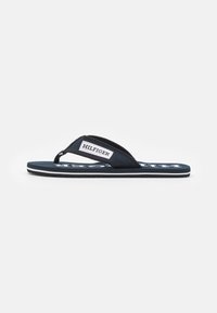 Marine flip-flop sandaler med en tekstureret rem og et hvidt logo-patch; har en sort sål med en hvid accentlinje.