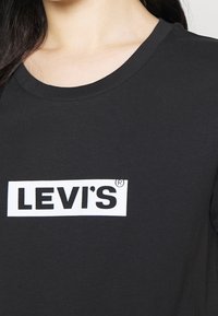 Černé bavlněné tričko s kulatým výstřihem, opatřené výrazným bílým logem Levi's na hrudi. Hladký povrch a ležérní design.