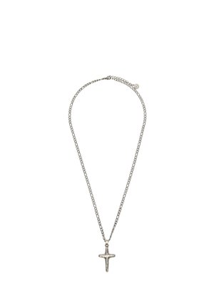 Srebrna ogrlica z verižico in preprostim, rahlo nepravilnim križem, ki visi na sredini na belem ozadju.