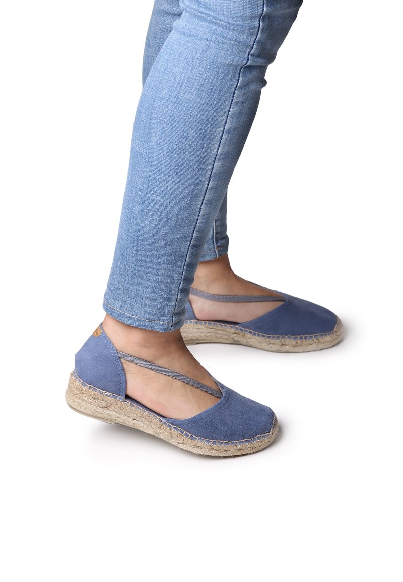 Sinisten espadrille-kenkien pehmeä mokkanahka-yläosa, kudottu juuttipohja ja harmaat joustimet. Alhainen korko, avonainen takapuoli ja pyöristetty varvas.