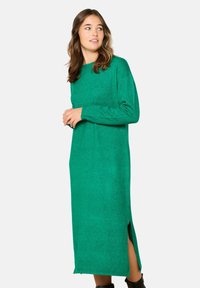 Abito verde a maniche lunghe in misto lana con taglio dritto, spacchi laterali e scollatura arrotondata, con una finitura testurizzata.