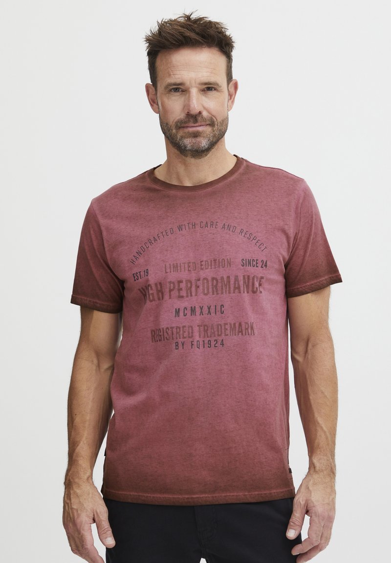 Kortsleeved maroon t-skjorte med en falme design. Har trykt tekst i mørk brun, rund hals og en avslappet passform.