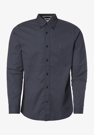 Granatowa koszula zapinana na guziki z małym białym wzorem w kropki, z kołnierzykiem w kształcie ostrego szpica i długimi rękawami, wykonana z lekkiej tkaniny.
