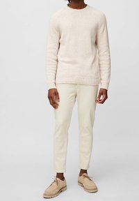 Licht beige gebreid sweater met een textuurpatroon, ronde halslijn en ribgebreide manchetten, gecombineerd met crèmekleurige slim-fit broeken en tan veterschoenen.