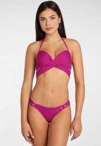Magenta bikiny s krúteným dizajnom na vrchu a bočnými výrezmi na spodnej časti. Vyrobené z hladkého materiálu s tenkými ramienkami a minimálnym kovovým príslušenstvom.