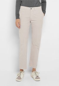 Beige kordfløyelsbyxor med rak passform, fransad fåll och sidofickor. Matchas med vita och grå låga sneakers.