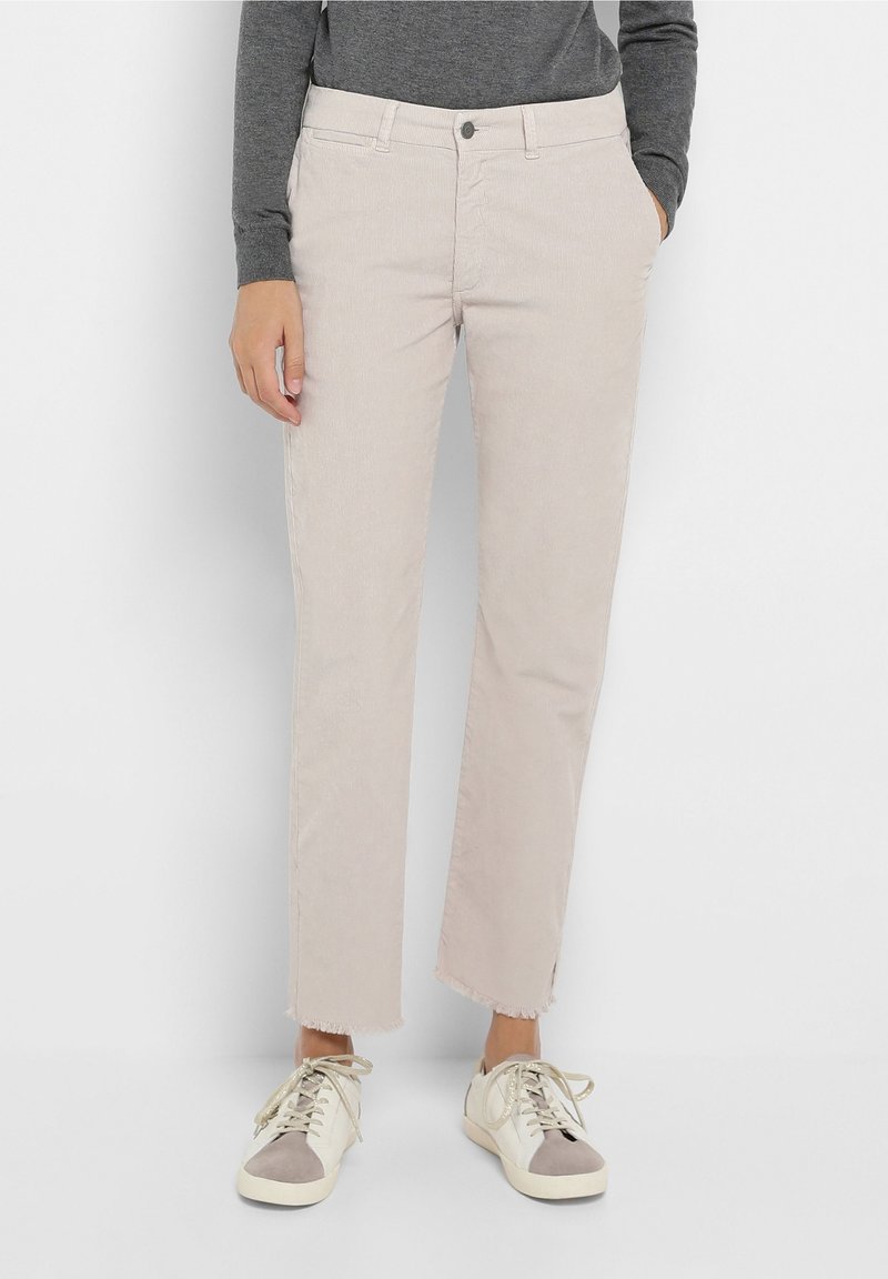 Beige kordfløyelsbyxor med rak passform, fransad fåll och sidofickor. Matchas med vita och grå låga sneakers.