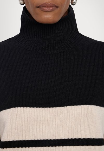 Black and beige striped turtleneck sweater with ribbed texture. Features wide cream stripe with a narrow black stripe below.