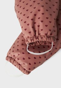 Rosa vattentäta vantar med röda hjärtan och elastiska handledsmuddar med fästa vita fotremmar.