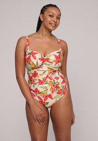 Bañador de una pieza en un tono melocotón claro con estampado floral que presenta flores rojas y hojas verdes. Tejido suave con tirantes ajustables y diseño fruncido.
