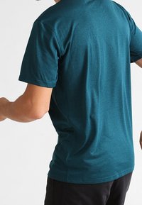 Teal t-shirt med kort ärm och rundad halsringning. Tillverkad av ett mjukt, andningsbart material med en slät textur och en avslappnad passform.