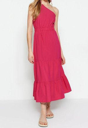 Fuchsia maxi-jurk met één schouder, een elastische taille, gelaagde ruffles aan de zoom en lichte stof. Draagt met sandalen met bandjes.