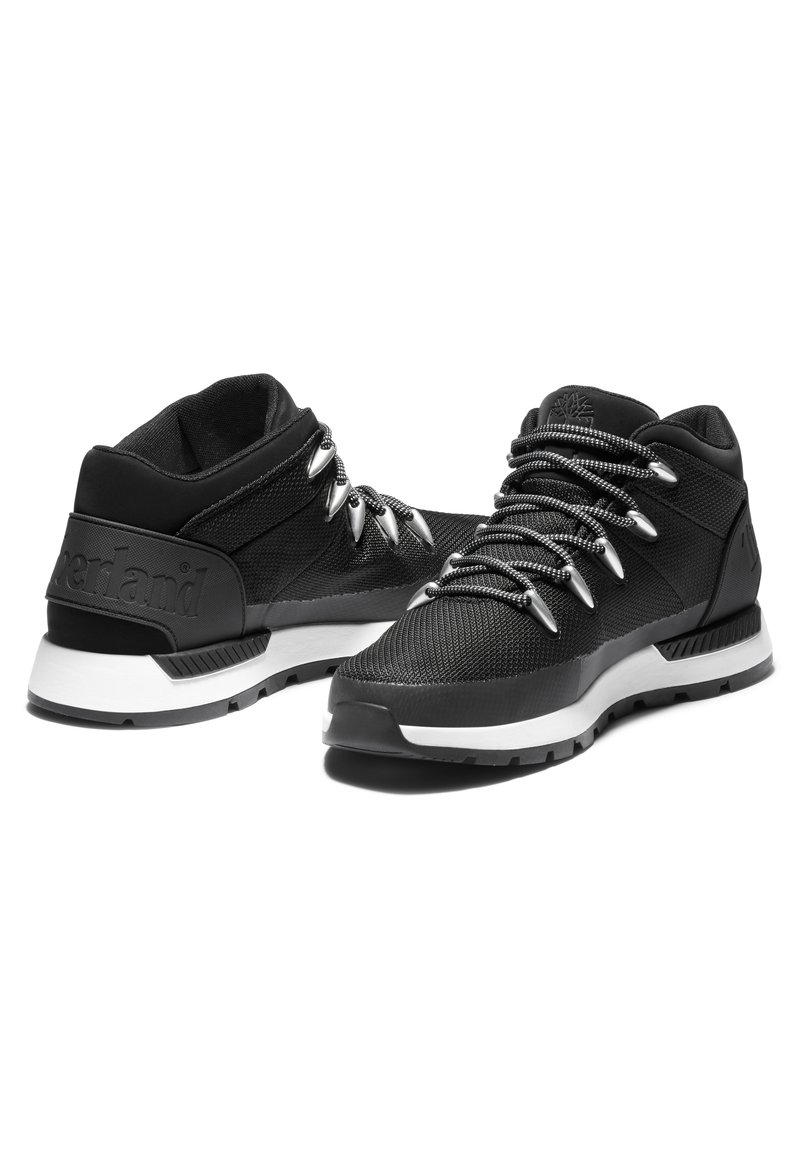 Zapatillas deportivas negras con una parte superior texturizada, cordones plateados y una media suela blanca acolchada. Presenta un logo en el talón y una suela de goma duradera.