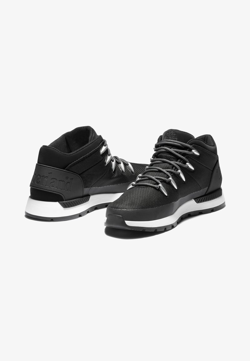 Czarne buty sportowe z teksturowaną cholewką, srebrnymi sznurowadłami i wyściełaną białą podeszwą środkową. Posiadają logo na pięcie oraz trwałą gumową podeszwę.