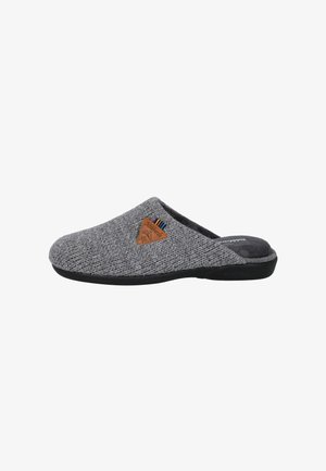 Zapatilla de punto gris con parte superior texturizada, suela de goma negra y una etiqueta triangular marrón con rayas multicolores en el costado.
