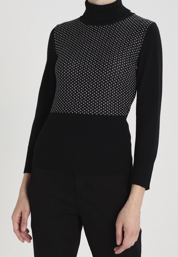 Sweater noir à col roulé avec une partie supérieure texturée et à motifs comportant des points blancs ; design côtelé sur le bas du corps et les manches.