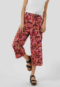 Pantalon culotte à imprimé floral dans des tons de rose, orange et marron. Présente une silhouette à jambes larges et une taille haute avec une fermeture à bouton.