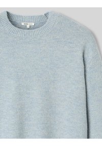 Pull oversized bleu clair avec un col rond côtelé. Fabriqué en tissu doux et texturé avec un subtil motif chiné.