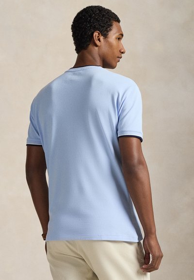 Ανοιχτό μπλε πόλο μπλουζάκι με κοντά μανίκια, ριμπ γιακά και ναυτικά στοιχεία, κατασκευασμένο από απαλό ύφασμα. Το σχέδιο διαθέτει άνετη εφαρμογή.