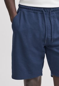 Tmavomodré šortky z mäkkej látky, s elastickým pásom so šnúrkou a bočnými vreckami.