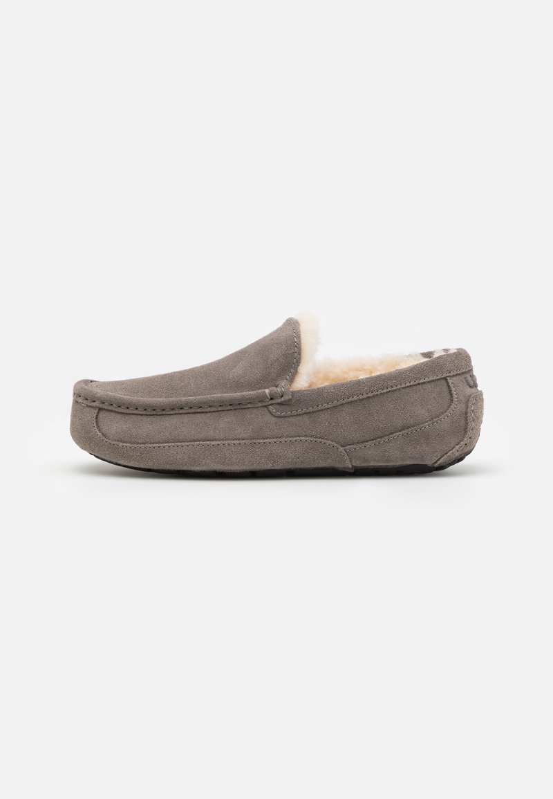 Szürke nubuk slip-on papucsok, puha, krémszínű belső béléssel, lekerekített orral és alacsony profilú kialakítással. Textúrált gumi talp a tapadásért.