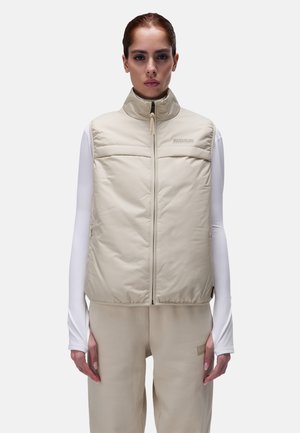 Beige padded vest with a high collar, front zip, and two horizontal chest pockets. Layered over a white long-sleeve top. Smooth texture.
