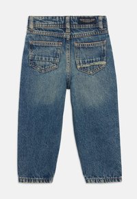 Jean en denim bleu avec une coupe décontractée, dotés de deux poches arrière, d'une couture visible et d'un design de jambe fuselée. Lavage classique délavé.