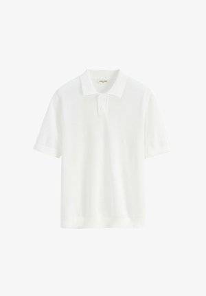 Polo blanc à manches courtes avec une patte de boutonnage à deux boutons et un tissu en maille texturée, étiqueté « FRILIVIN ».