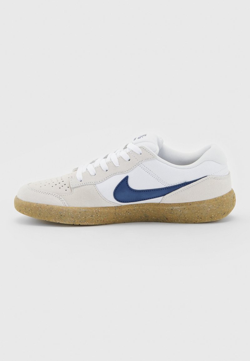 Baskets Nike blanches et beiges avec logo swoosh bleu et semelle texturée marron clair vues de profil sur un fond uni.