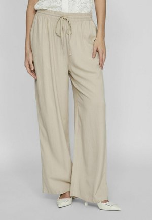 Beige weite Hosen aus leichtem Stoff mit elastischem Bund und Kordelzug, die eine glatte Textur und ein minimales Design aufweisen.