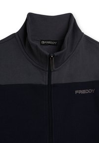 Chaqueta con cremallera de color azul marino oscuro con detalles en gris, que presenta un cuello alto, textura suave y el logo de Freddy en el pecho. Se ve la cremallera.
