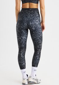 Hoge taille leggings in een zwart en grijs luipaardpatroon, met een soepele textuur en een aansluitend ontwerp. Accentueert met een logo op de tailleband.